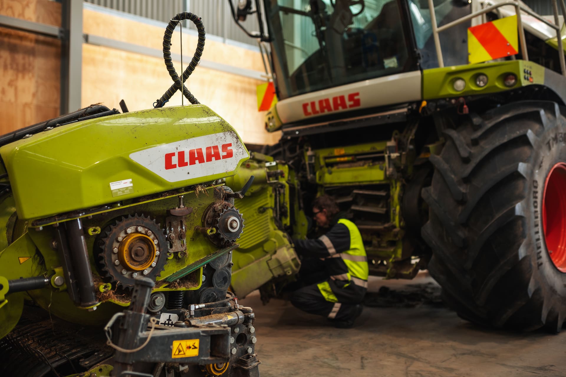Claas machine motor with service technician working on machine in background - landscape