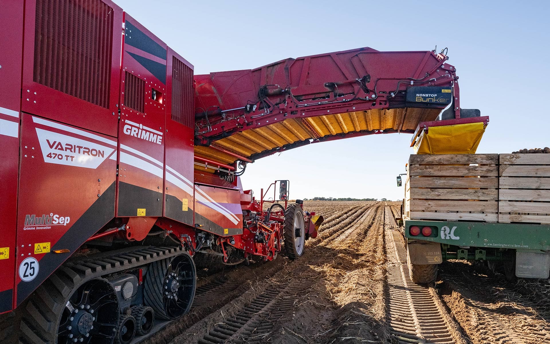 image of grimme machine unloading potatoes into crate on back of truck